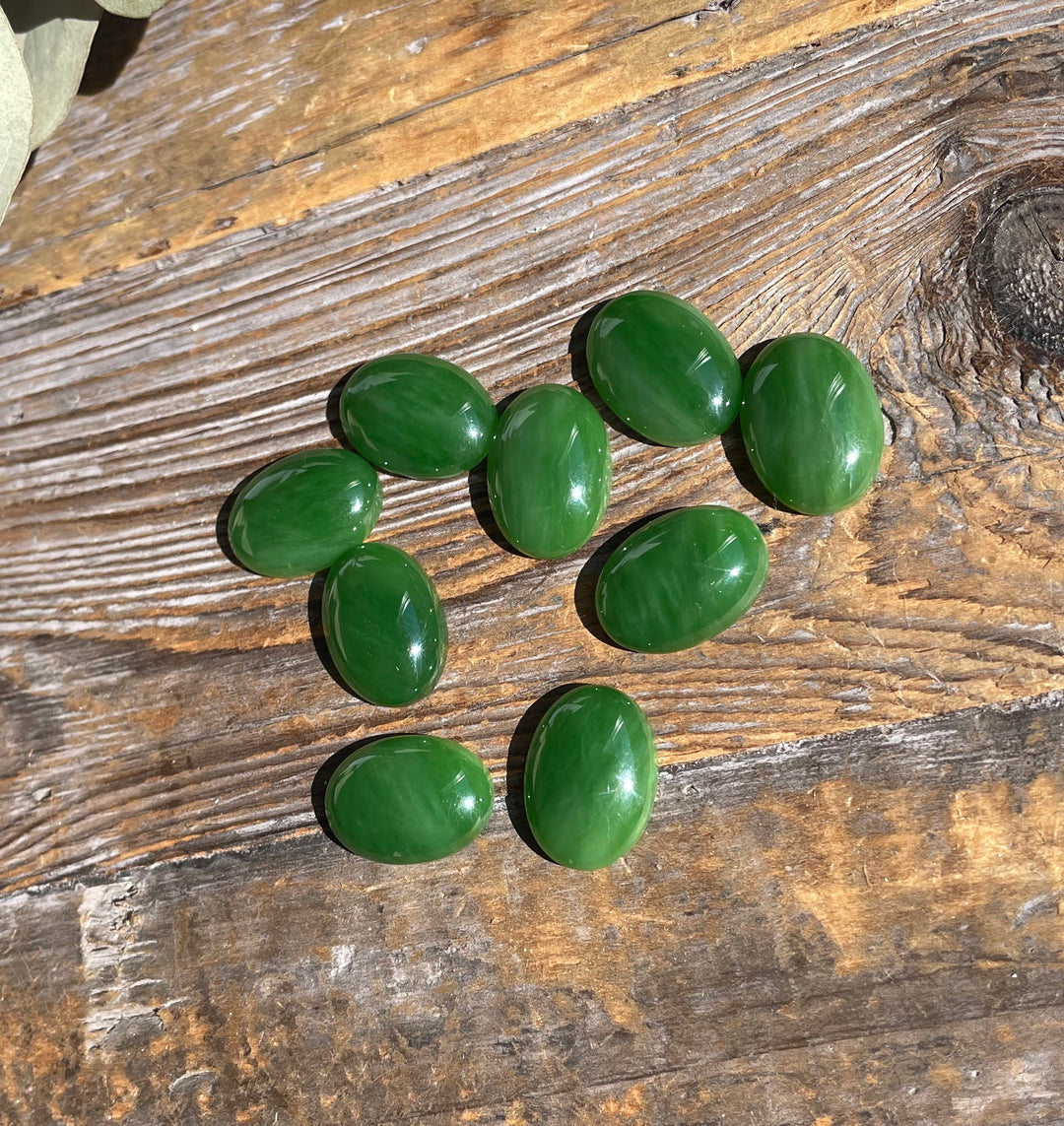 AA Grade Siberian Jade oval cabochons 18x13mm arranged on rustic wood surface