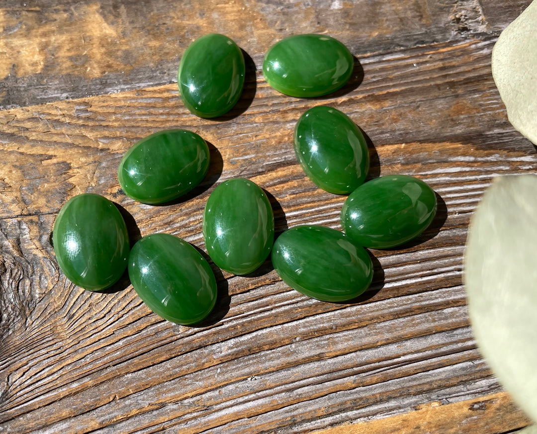 Group of AA Grade Siberian Jade oval cabochons 18x13mm arranged on a wooden surface