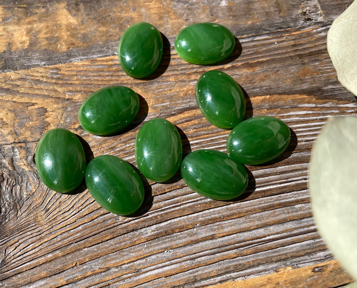 Group of AA Grade Siberian Jade oval cabochons 18x13mm arranged on a wooden surface