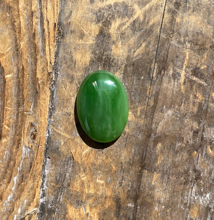 AA Grade Siberian Jade oval cabochon 18x13mm on rustic wood surface