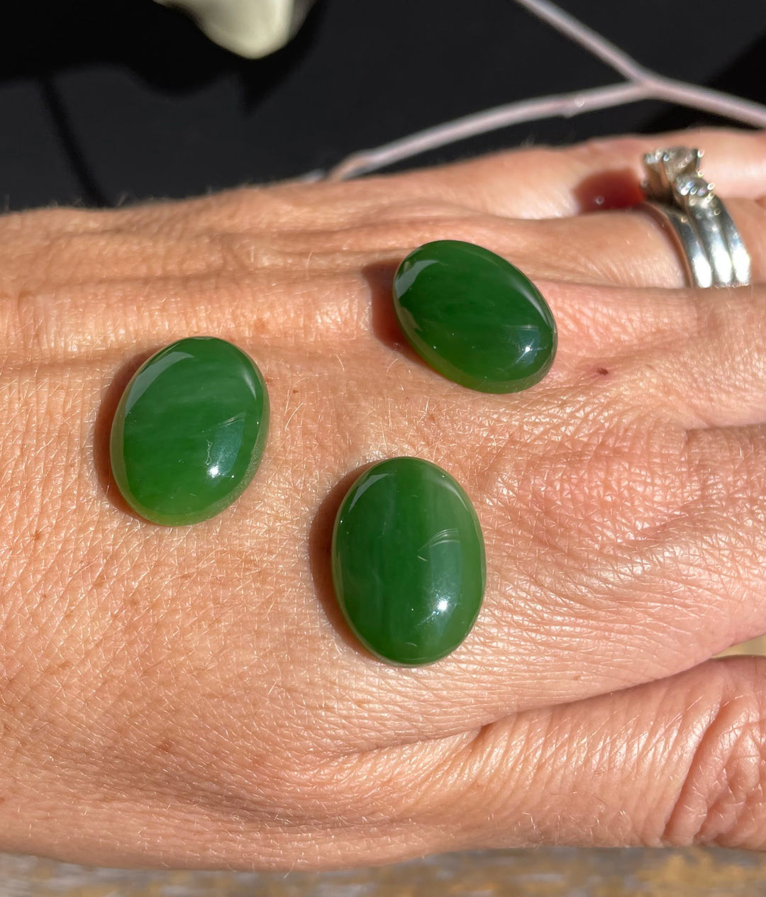 Three AA Grade Siberian Jade oval cabochons 18x13mm on a person&