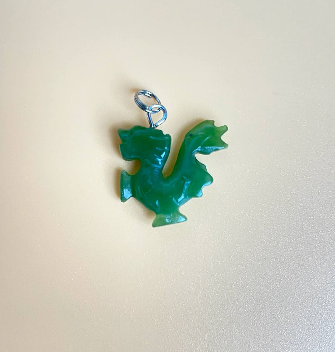 Green jade dragon walking charm with a silver loop for attaching to a bracelet or necklace