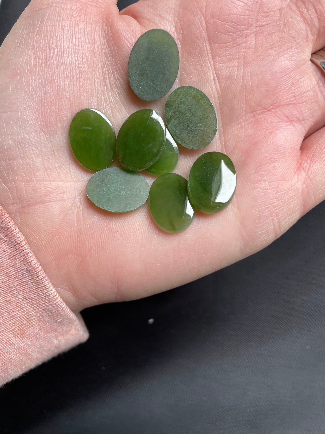 Green jade flat top oval cabochons held in the palm