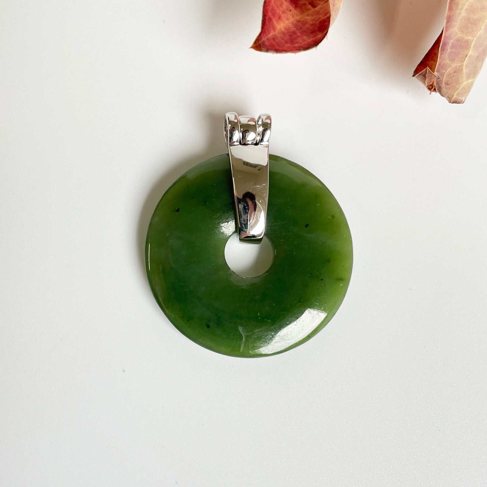 Green jade donut pendant with a silver bail