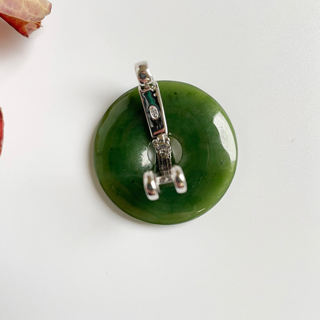 Green jade donut pendant with silver bail viewed from the side