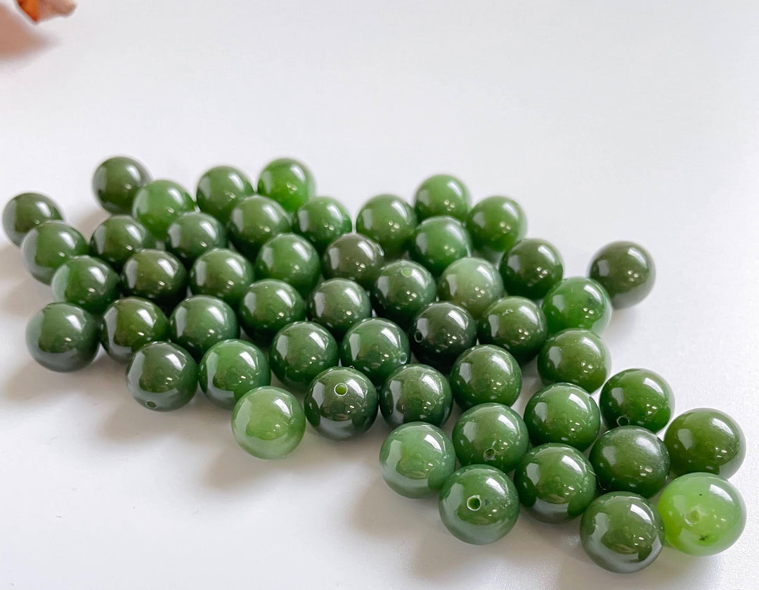 A+ Half Drilled 10mm Canadian Jade beads arranged on white background showing drilled holes