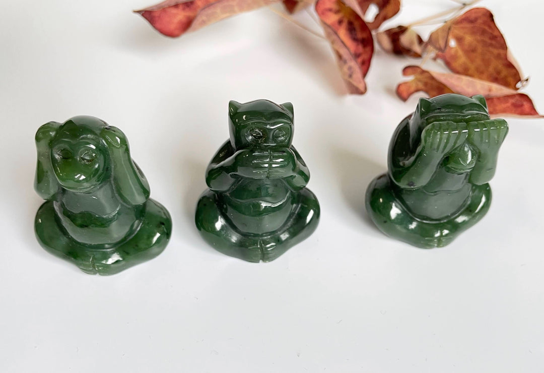 Three dark green jade monkey figurines representing see no evil hear no evil and speak no evil.