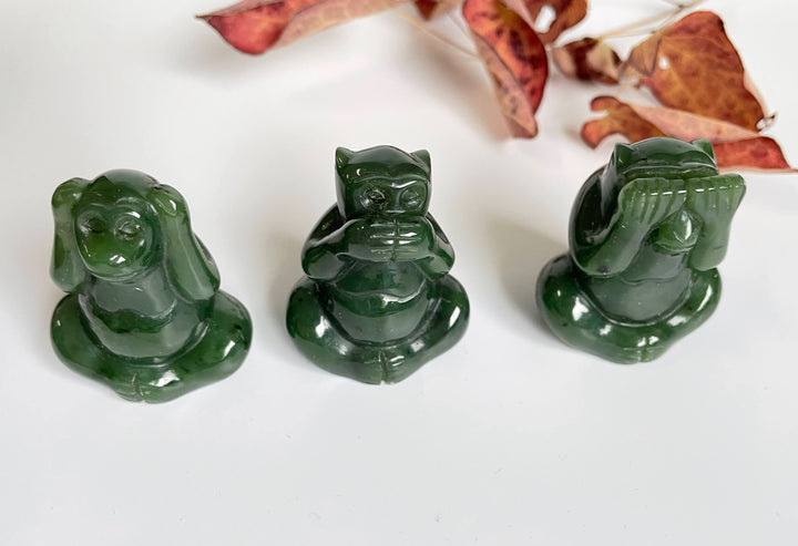 Three dark green jade monkey figurines representing see no evil hear no evil and speak no evil.