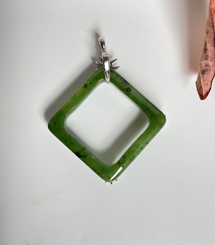 Green jade square pendant with silver flower accents at the corners and a floral bail