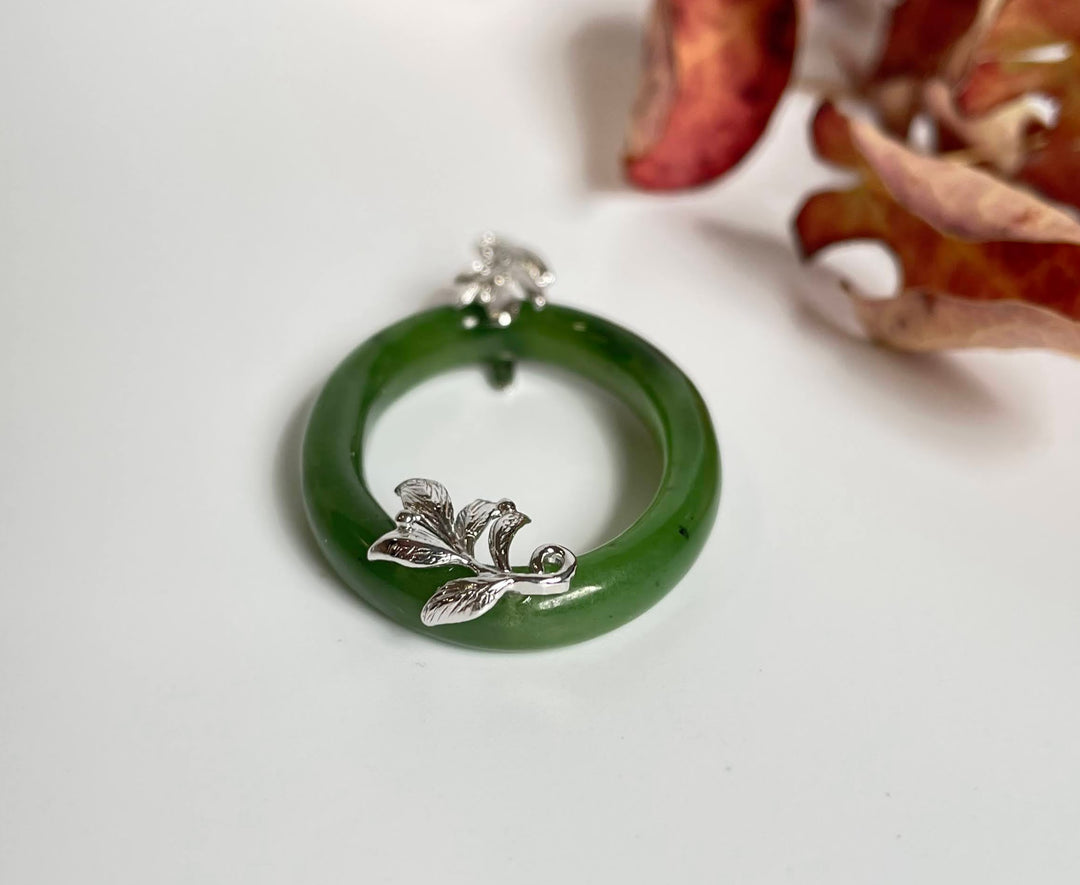 Close up of jade oval pendant showing silver leaf motif at bottom end