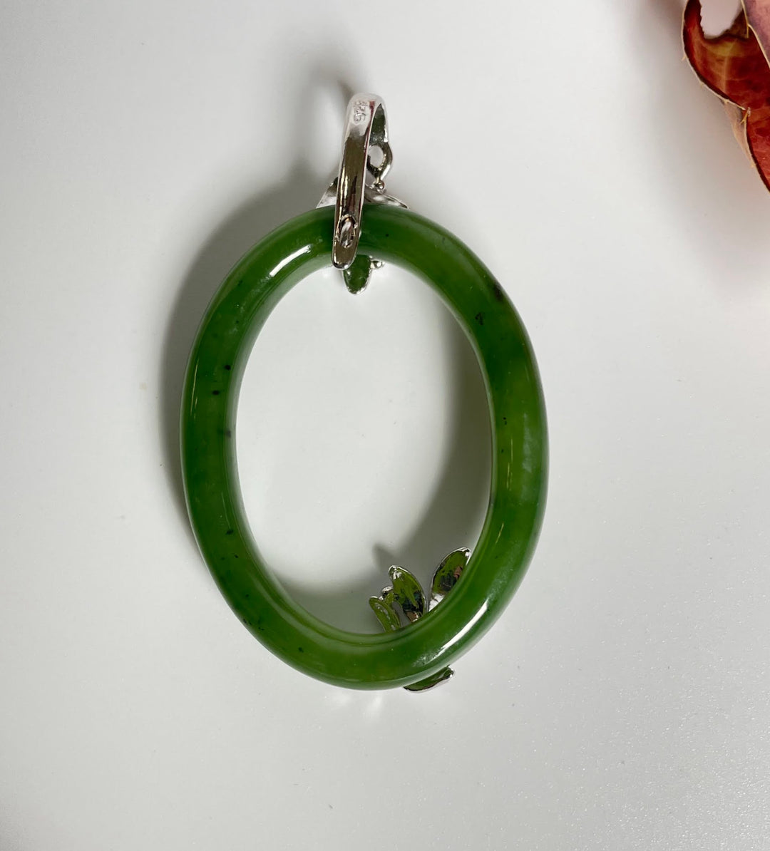 Vibrant green jade oval pendant in sterling silver with leaf accents.