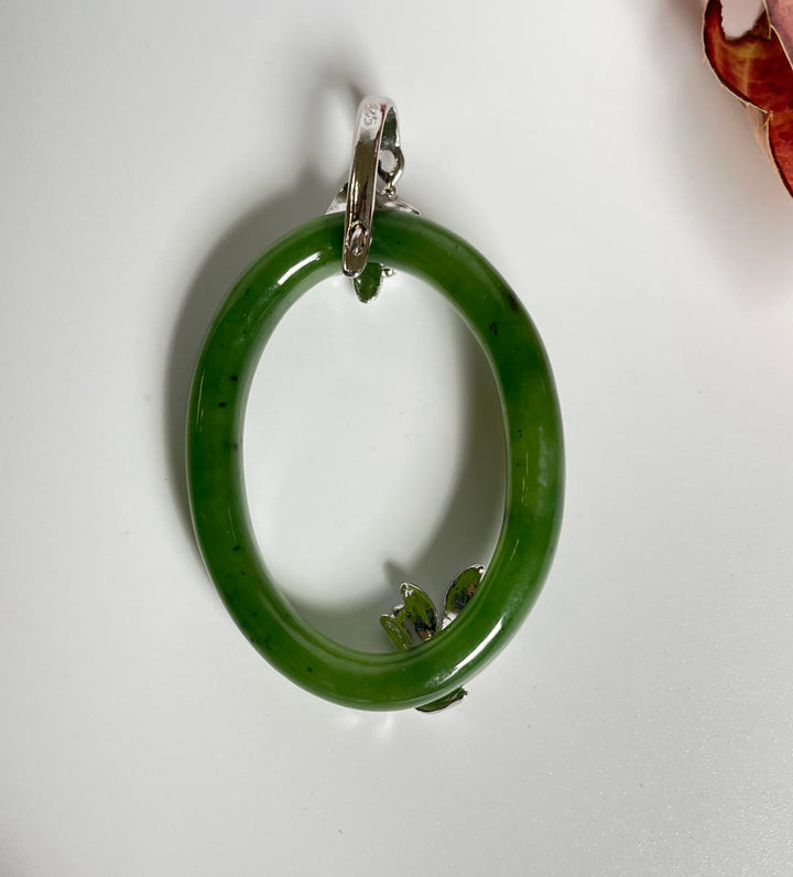 Vibrant green jade oval pendant in sterling silver with leaf accents.