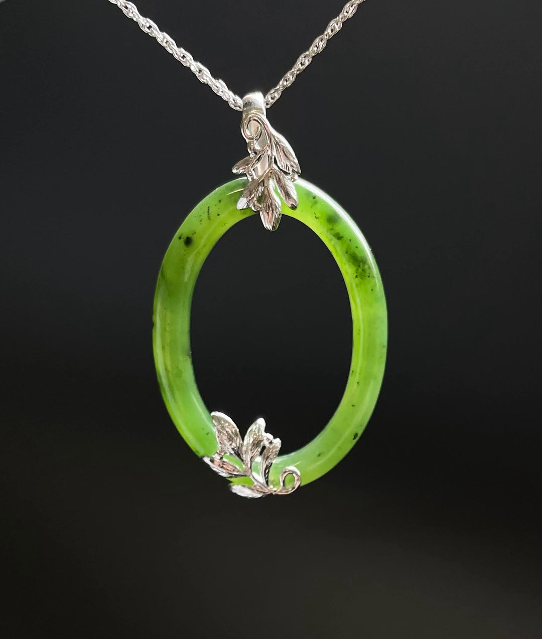 Jade oval pendant on a silver chain with decorative silver leaf caps at ends