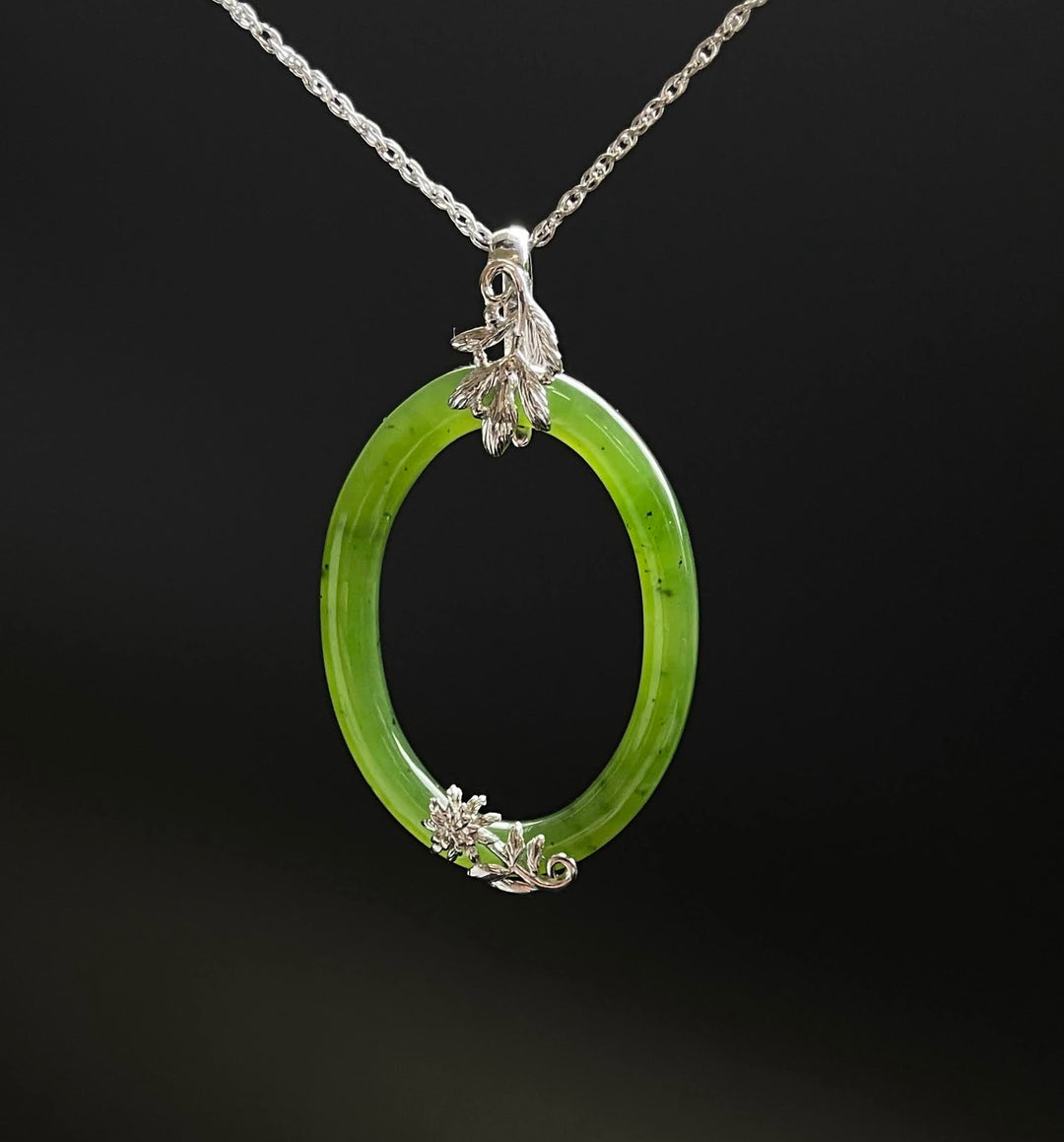 Bright jade oval pendant with silver leaf accents at top and bottom on a silver chain