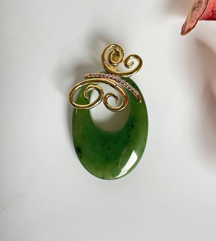 Green jade oval pendant with gold butterfly scrollwork and diamond accents.