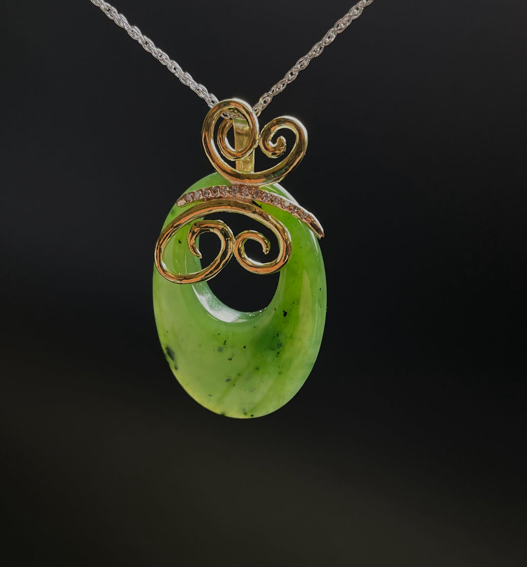 Jade Butterfly Pendant suspended on a silver chain with vivid green jade and gold filigree against a dark backdrop.