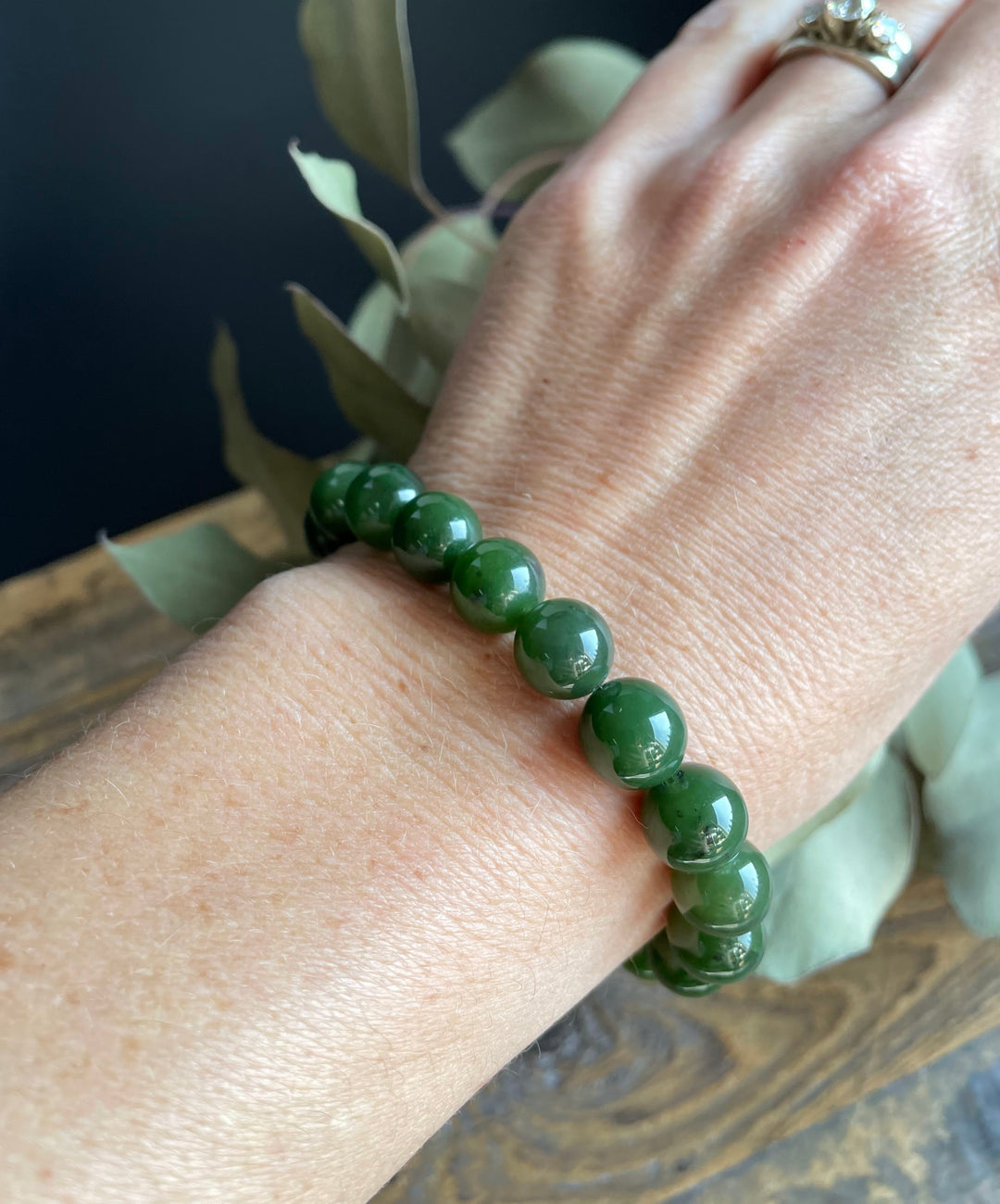 Close-up of a green bead mala bracelet worn on the wrist.