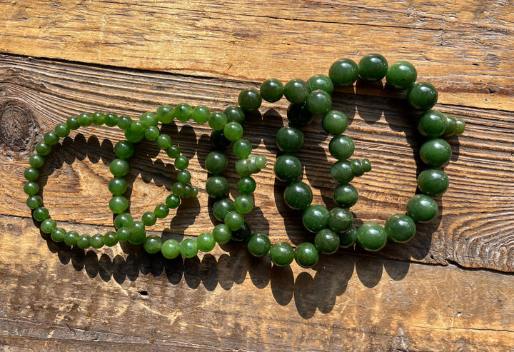 Green mala bead bracelets arranged on a rustic wooden surface.