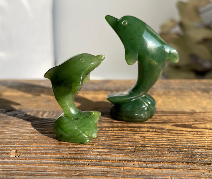 Two green dolphin figurines on a wooden surface.
