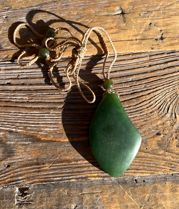 Green teardrop jade pendant on a knotted beige cord with small green bead accents