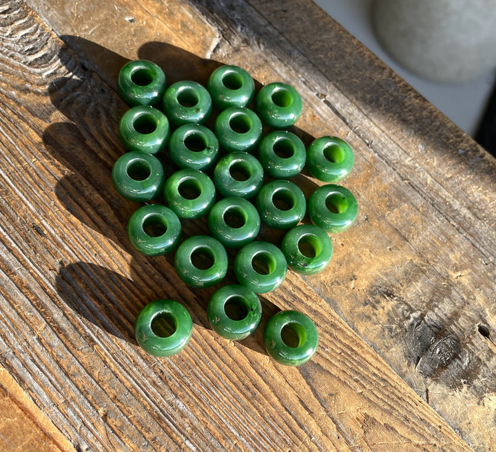 Pile of round hollow green jade beads on a weathered wooden surface