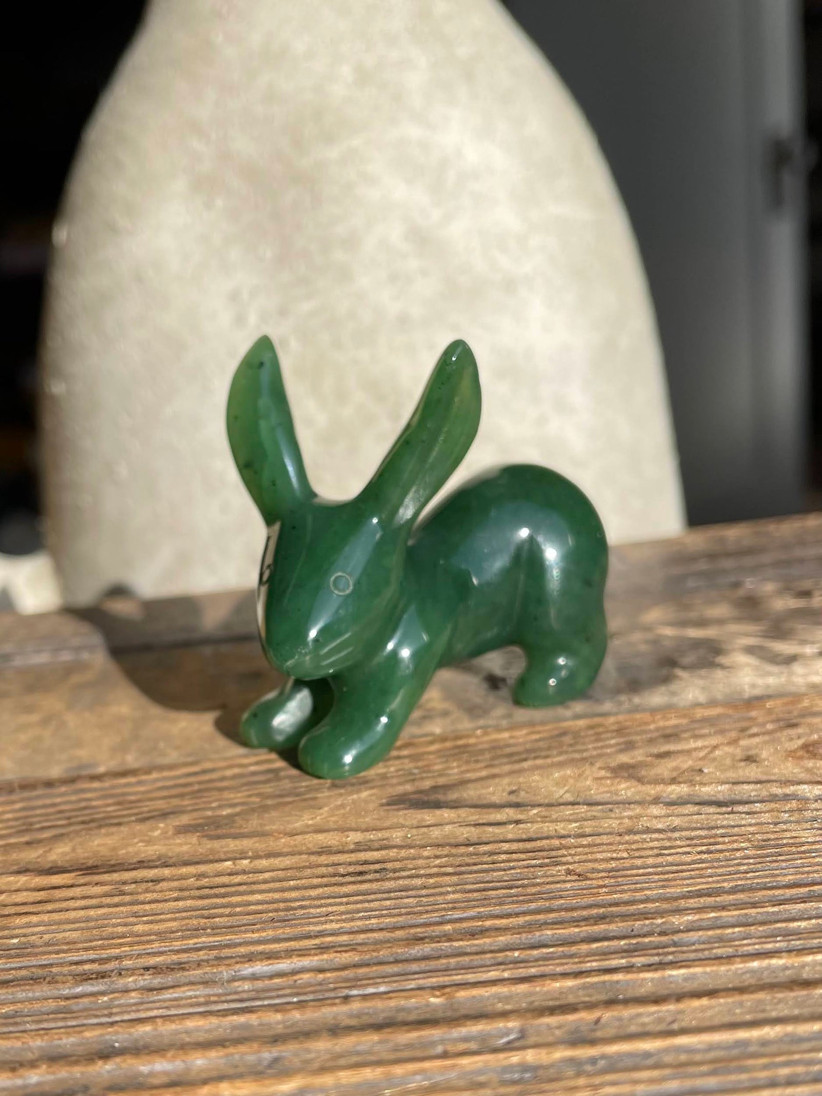 Green jack rabbit sculpture placed on a weathered wooden surface