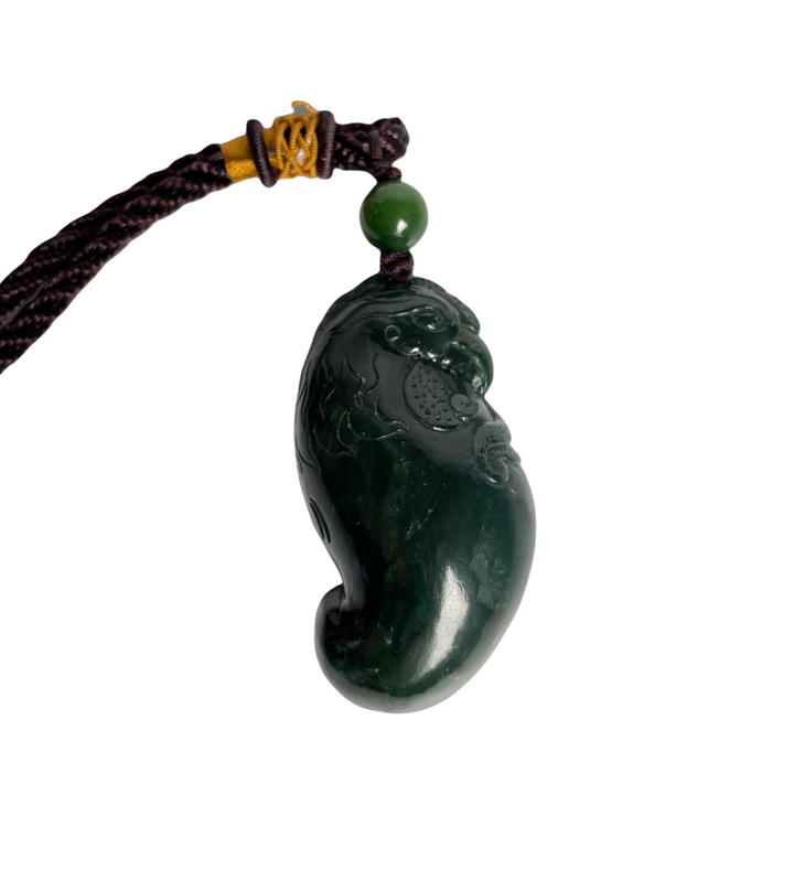 Dark green jade rooster pendant with carved details hanging from a braided brown cord and a green bead