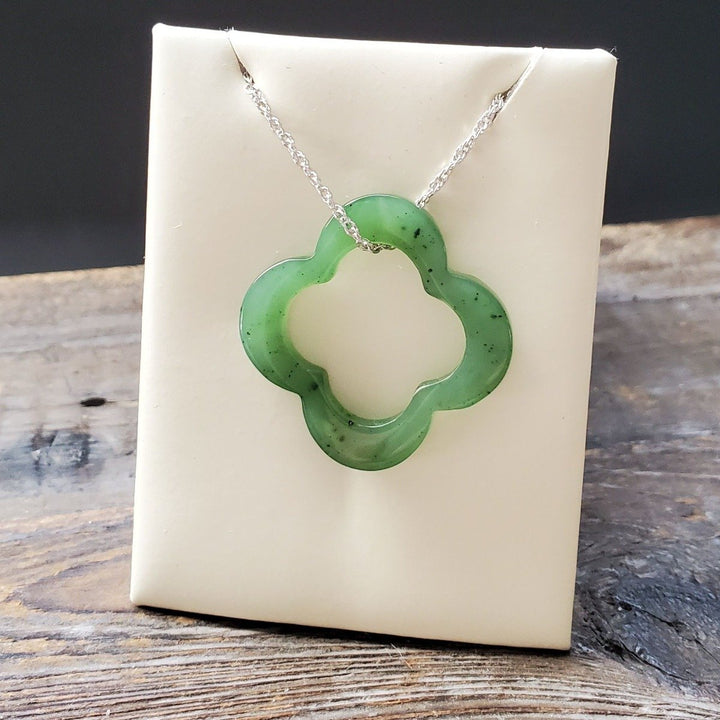 Green clover pendant on a silver chain displayed against a white display card.