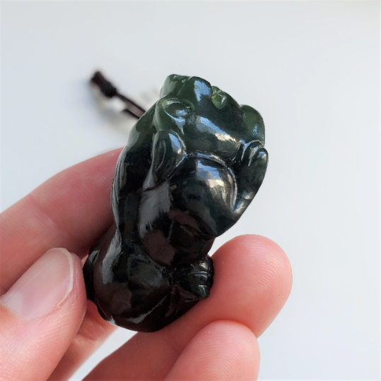 Front-angle view of dark green jade Pi Xiu pendant on cord with glossy finish