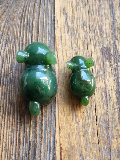 Top-down view of two green jade chinchilla figurines on a weathered wooden surface.