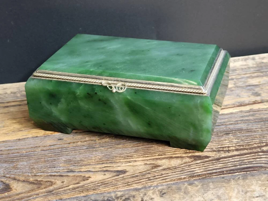 Siberian jade box with a green marbled lid and silver trim on a wooden surface