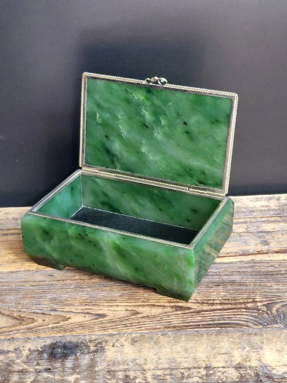 Siberian jade box with silver trim opened on a wooden surface.