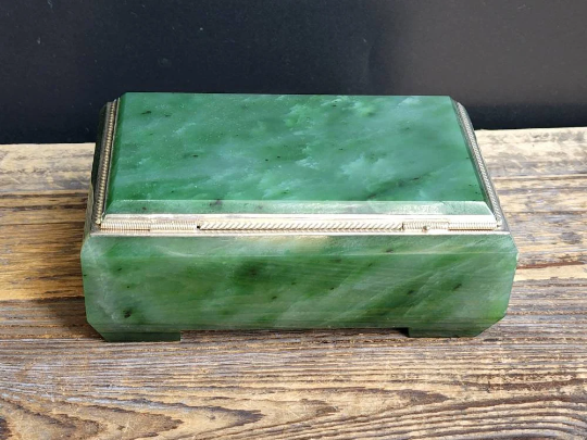Closed Siberian jade box with silver-edged trim displayed on a weathered wooden surface.
