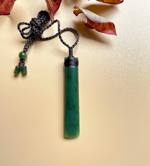Cylindrical green jade pendant on a black cord with bead accents