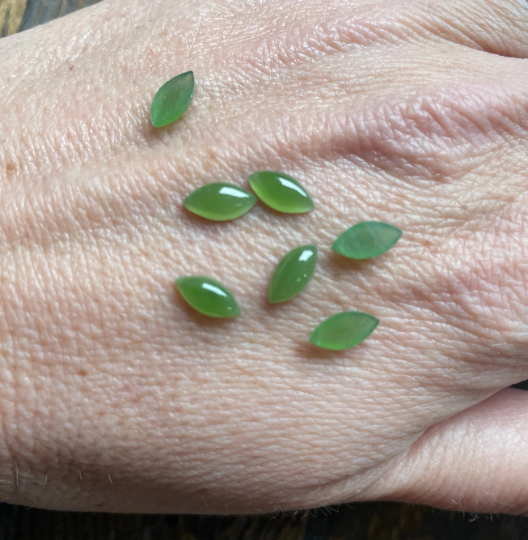 Bright green nephrite jade navette cabochons on skin, small marquise leaf shapes.