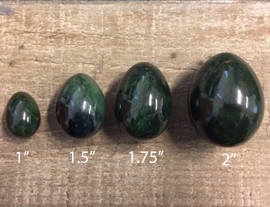 Four green eggs in increasing sizes set on a wooden surface.