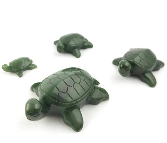 Group of four green turtle figurines of varying sizes on a white background