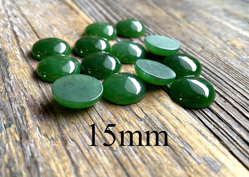 Green 15mm round cabochons scattered on a rustic wooden surface