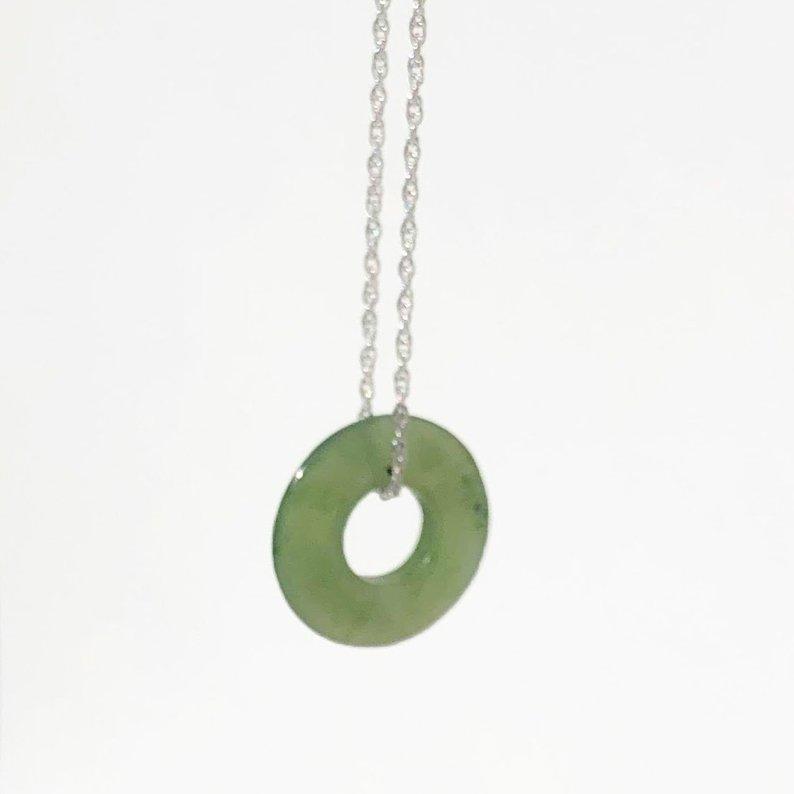 Green jade donut pendant with a central hole on a silver chain