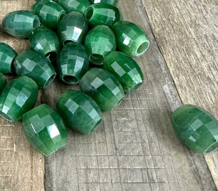 Faceted green Canadian jade bead 14x12mm with a central hole on a rustic wooden surface