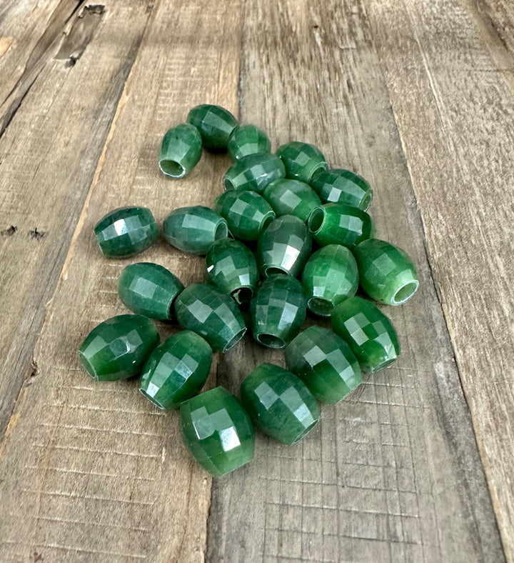 Cluster of faceted green jade beads with center holes scattered on a wooden board