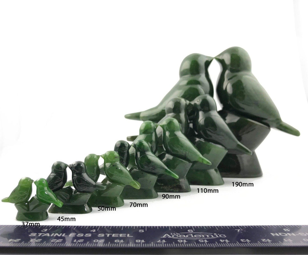 Green lovebird figurines in various sizes lined up with a ruler for scale.