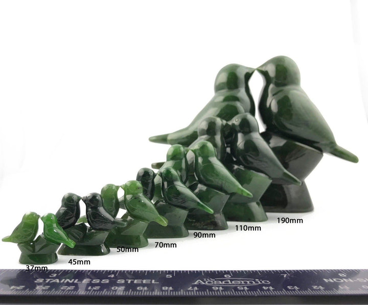 Green lovebird figurines in various sizes lined up with a ruler for scale.
