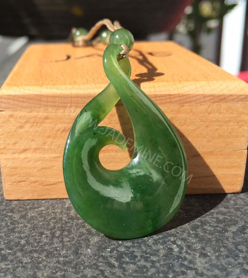 Deep green jade pendant with a smooth teardrop loop and central circular hole on a braided cord