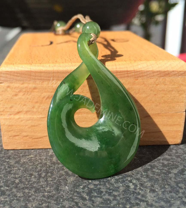 Deep green jade pendant with a smooth teardrop loop and central circular hole on a braided cord