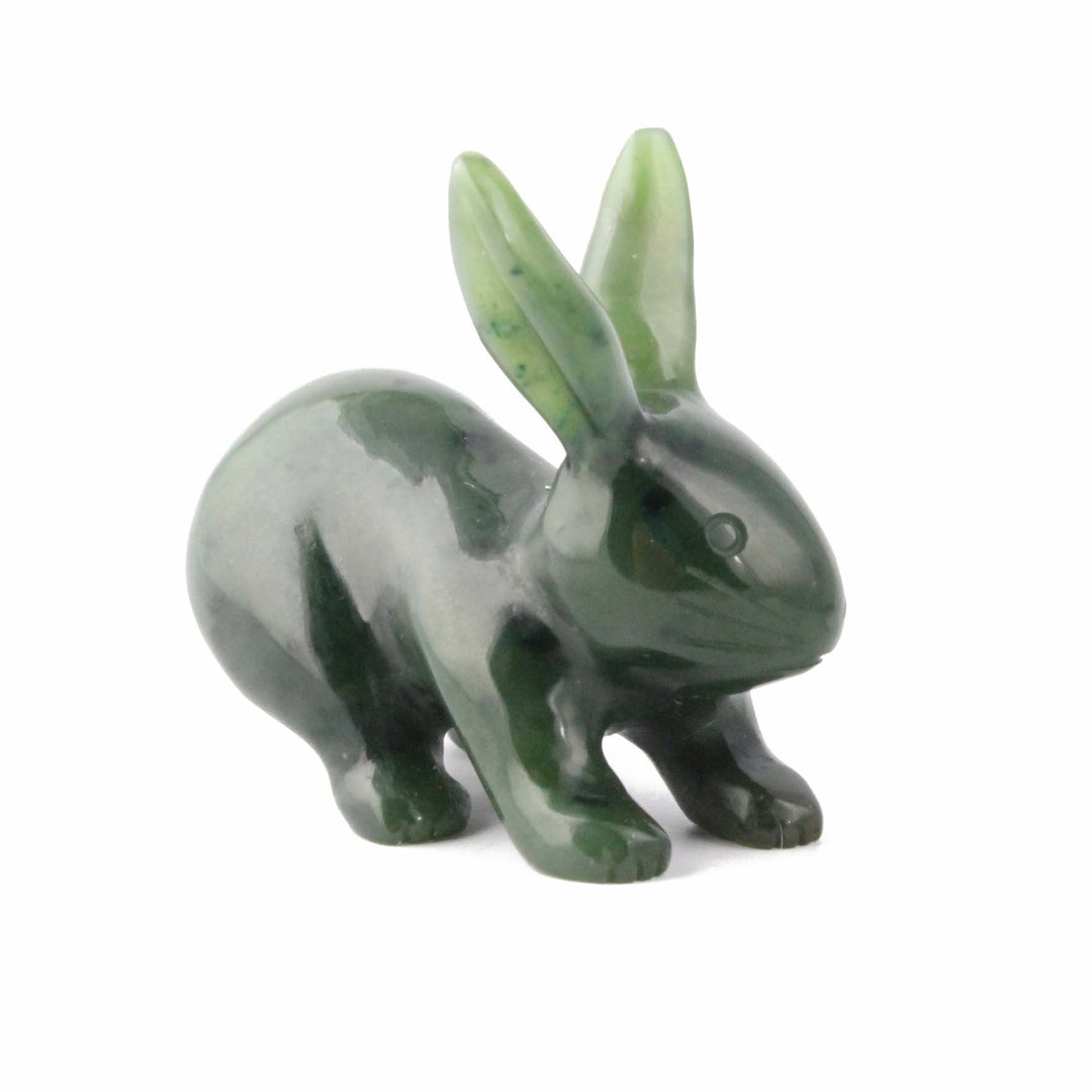 Dark green jade rabbit sculpture on a white background with ears raised