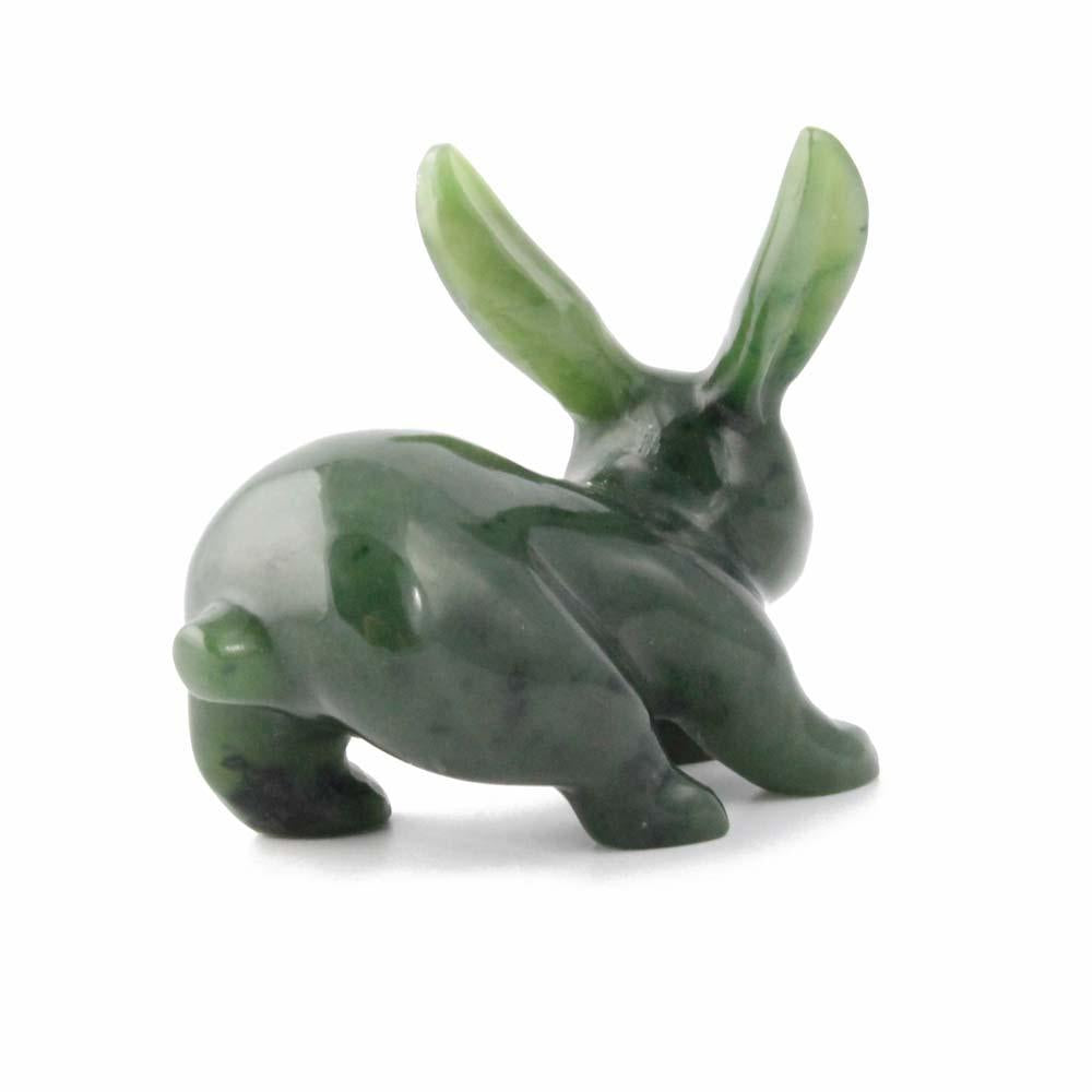 Side view of a green jade rabbit carving with ears upright on a white background