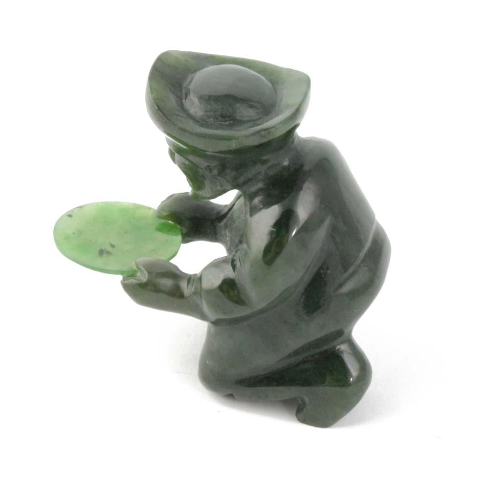 Side view of the green stone gold panner figurine kneeling and holding a pan.