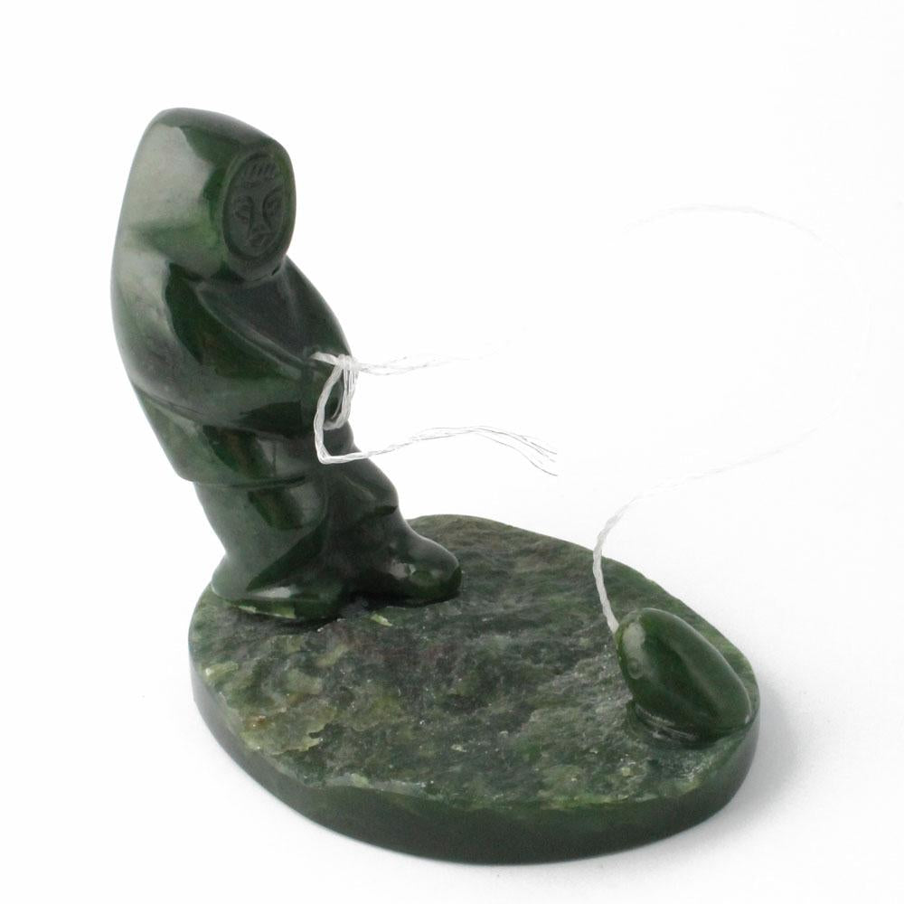 Canadian nephrite jade fisherman catching seal sculpture on a round base
