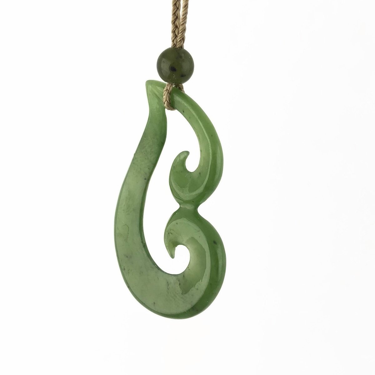 Green jade pendant with round top bead and curved hook shape on a natural cord.